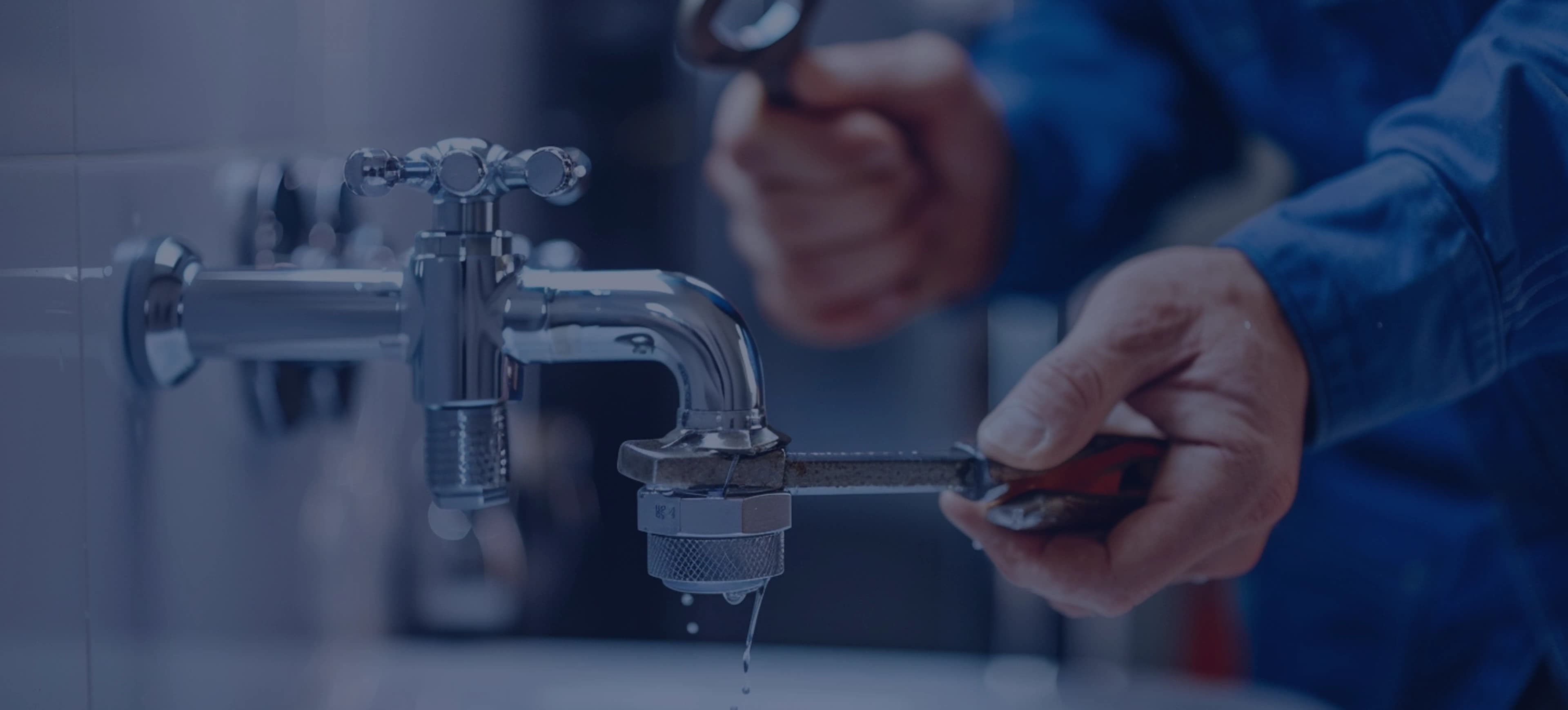 Plumber working on a chrome faucet with a wrench